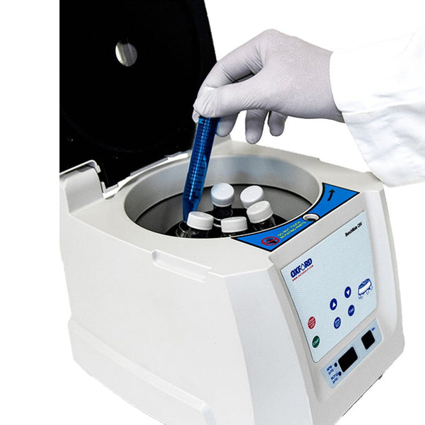 Centrifuge holding conical centrifuge tubes by Oxford Lab Products, with gloved hand inserting blue liquid sample tube.
