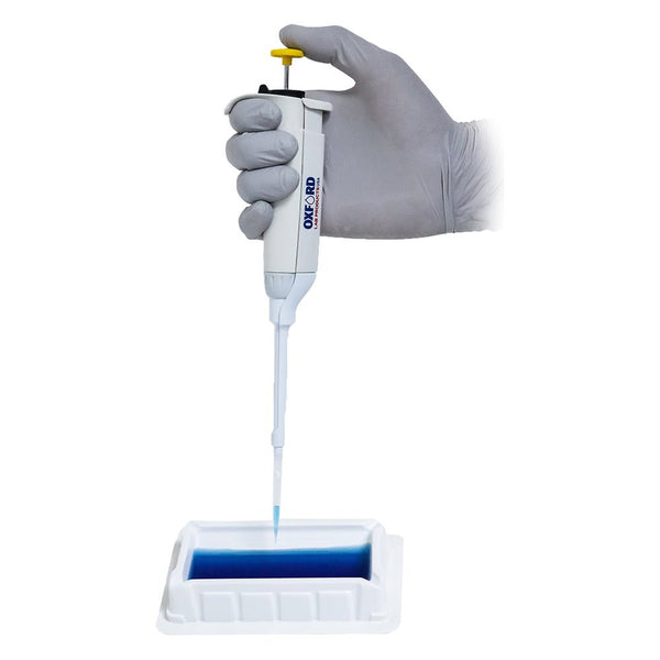 Single channel pipette by Oxford Lab Products with a gloved hand dispensing blue liquid into a white container.

