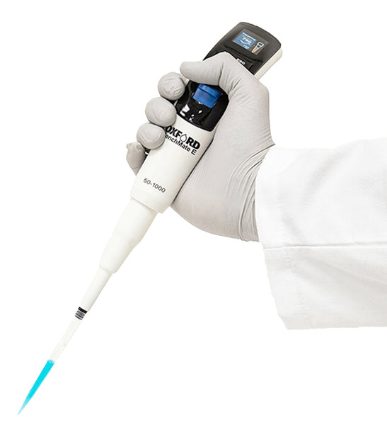 Electronic pipette by Oxford Lab Products held in gloved hand with blue liquid in the tip.
