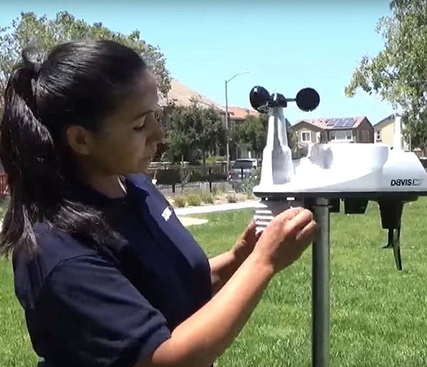 White weather station anemometer by Davis Instruments on a metal pole outdoors.
