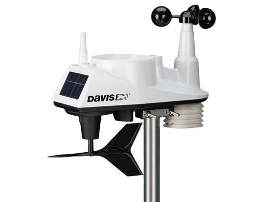 White wireless weather station by Davis Instruments with a solar panel and anemometer on a metal pole.
