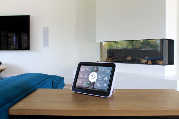 Weather data viewing console by Davis Instruments sitting on a wooden table in a modern living room.
