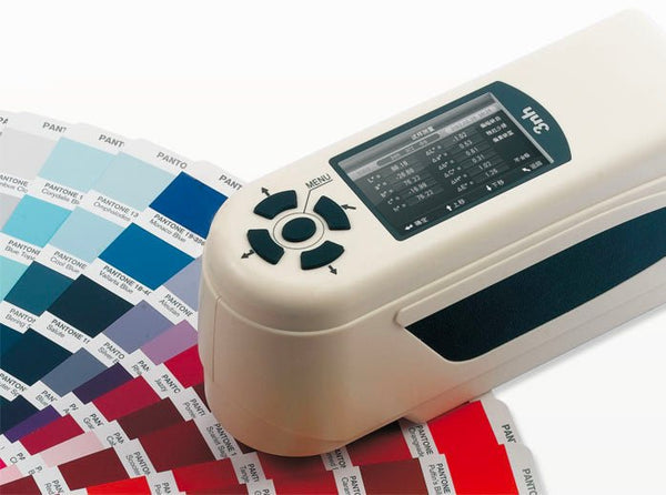 Precision colorimeter by 3nh sitting on Pantone color samples, with a digital display and arrow-button controls.
